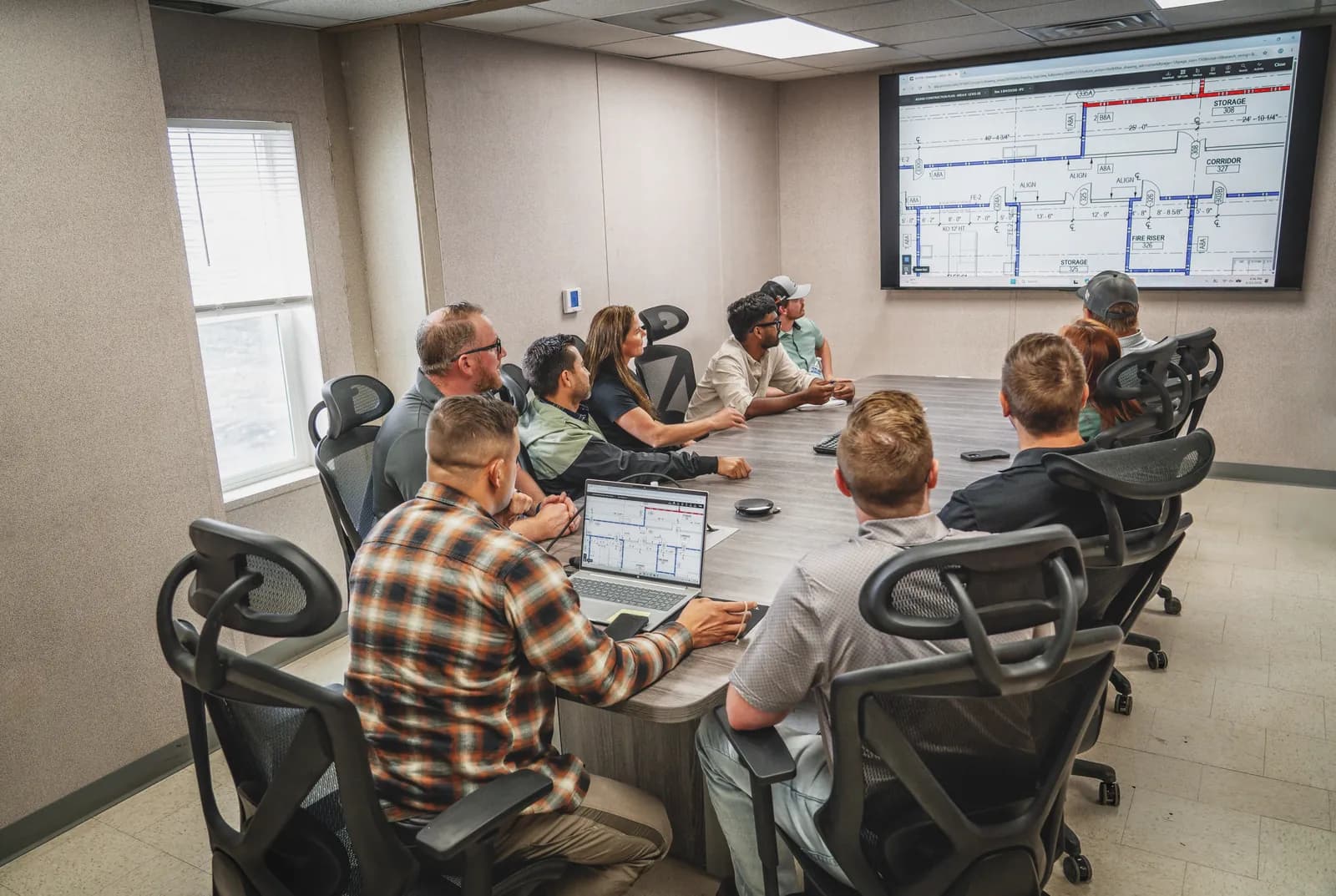 Project team reviewing building plans on screen in a jobsite conference room